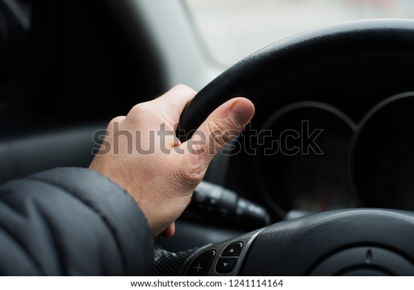 Hand on the steering\
wheel, close-up