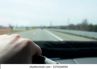 Hand on Steering Wheel While Driving Down a Road