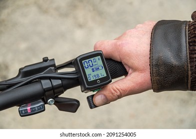 Hand on the trigger electronic accelerator of electric bike. Electric accelerator trigger and LCD display with speedometer, odometer, battery charge-discharge controller and other e-bike parameters