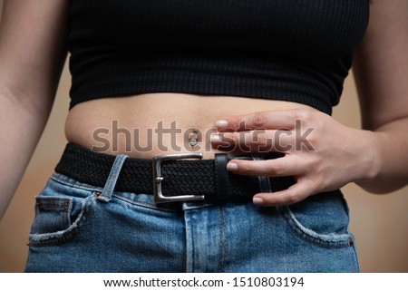 hand on waist of a young girl with navel Diamond piercing, close