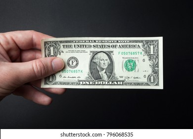 Hand And One Dollar Bill On A Black Background.