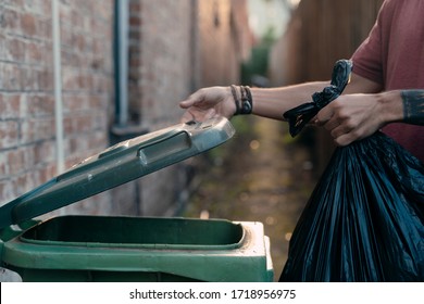 A hand opening a bin container lid before throwing the rubbish bag to the bin. The organic green waste is suitable for food scraps, garden waste, rotten meat... Waste management is crucial for ecology