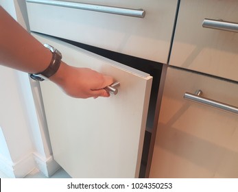 A Hand Is Opening The Cabinet. 