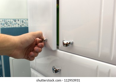 Hand Opening A Cabinet Door In Bathroom