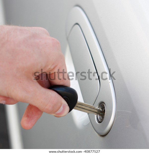 A hand opening a car\
door with a key