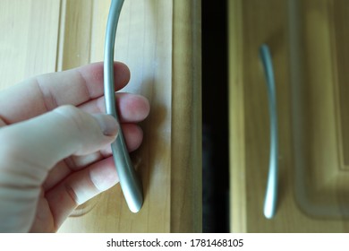 Hand opening the cupboard door in the kitchen. Close up view. - Shutterstock ID 1781468105