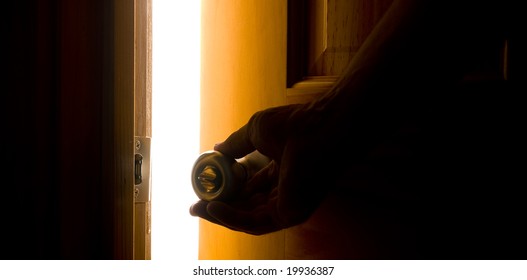 A Hand Opening A Door With A Bright Light