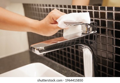 Hand opening the faucet with tissue wipe. Prevent coronavirus infection concept. Selective focus on wipes