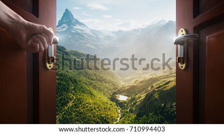 hand opens empty room door to nature and mountains