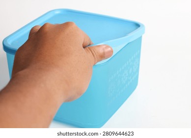 hand opens the lid of a square snack jar against a white background.