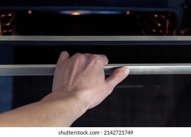 The Hand Opens The Oven Door. Kitchen Equipment.