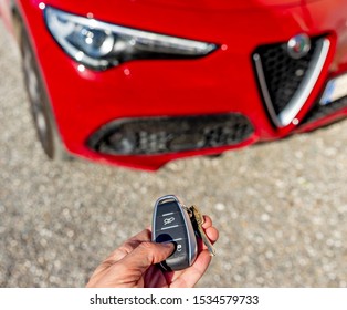 A hand operates the remote control of a beautiful red Italian sports car Alfa Romeo Stelvio