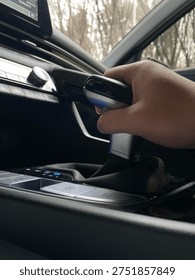 Hand Operating Automatic Gear Shift in Modern Car Interior
