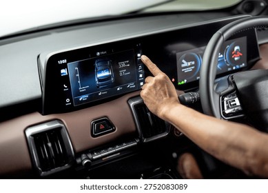 Hand operating infotainment touchscreen inside electric vehicle showing energy usage and driving range on digital dashboard display.
