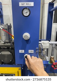 A engineer’s hand operating the nip roll machine switch on an industrial production line. The close-up shot highlights factory automation, precision control, and manufacturing process in an industrial environment.