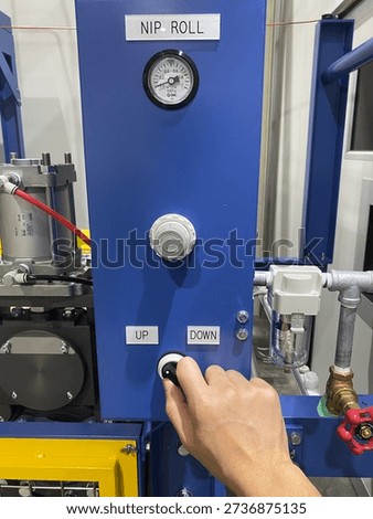 A engineer’s hand operating the nip roll machine switch on an industrial production line. The close-up shot highlights factory automation, precision control, and manufacturing process in an industrial environment.