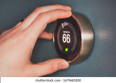 Hand Operating Smart Thermostat To Save Money