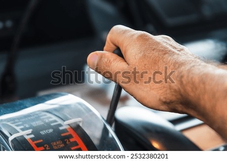 The hand of an operator grips the engine telegraph lever on the bridge of a merchant ship, ready to issue commands to control the main engine's speed, embodying precision and responsibility at sea.