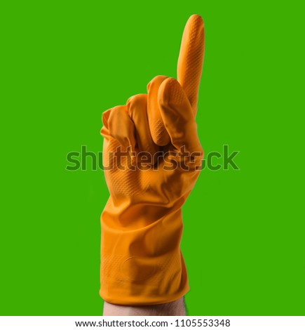 Hand with orange rubber gloves points upwards with index finger, green background
