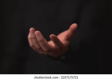hand outstretched in gesture of giving or receiving, black background, business theme, offer, opportunities.