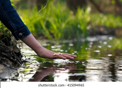 Hand Over The Water. Hand Female, Finger Ring. Water Is Green, Summer. Feng Shui