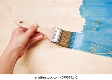 Hand painting blue color on wooden table use for home decorated. House renovation. Half - painted surface. Smear of paint brush