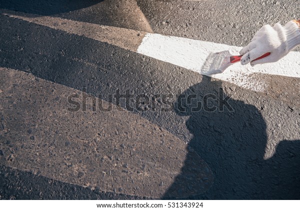 hand painting Road car speed limit and anti slip\
out of the lane.\
Road worker painting white color line with paint\
brush on the street\
surface