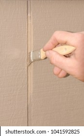 Hand Painting T111 Siding On A House, Ensuring To Get Paint In The Grooves