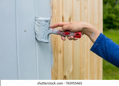 Hand Paints A Wooden Facade With A Brush