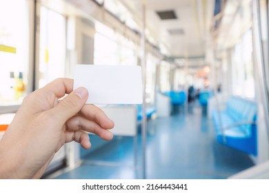 Hand Of A Passenger Holding White Empty Card For Contactless And Cashless Paying For Modern Urban Transport System In The City. Inside Interior Of The Metro Or Tram Coach