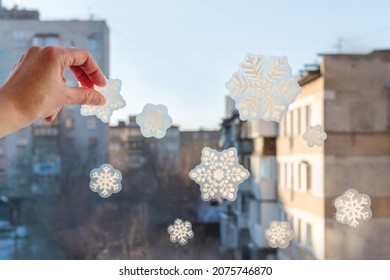 Hand pasting hand-made snowflake stickers on the window of a house. Snowflake pattern on window glass. - Powered by Shutterstock