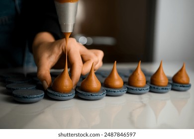 Hand of pastry chef filling macarons with cream on a kitchen - Powered by Shutterstock