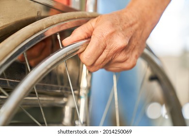 Hand Of A Patient On The Tire Of A Wheelchair As A Symbol For Disability And Paraplegia