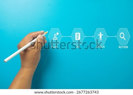 A hand with a PDCA (Plan Do Check Act) cycle diagram. A concept for continuous improvement (Kaizen), business process management, and quality control. A strategic framework.,Topview with copyspace.