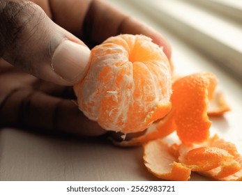 Hand peeling juicy clementine next to window