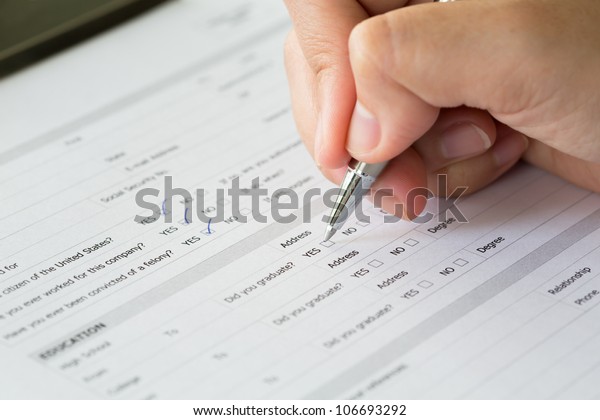 Hand
with pen over blank check boxes in application
form