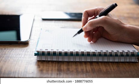 Hand with pen writing on notebook