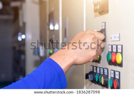 Hand of people key switch select mode in electrical control panel contains switch buttons for operating industrial machine and factory equipment in industry