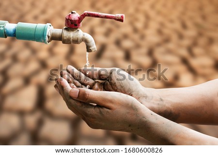 Hand of people wating for a drip of water from a faucet at desert. Climate change, water scarcity and crisis concept.