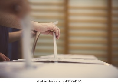 Hand einer Person, die während der Abstimmung an einem Wahllokal eine Stimmabgabe abgibt.