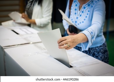 Hand of a person casting a ballot at a polling station during voting. - Shutterstock ID 446190286