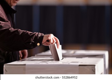 Hand of a person casting a vote into the ballot box during elections - Shutterstock ID 552864952