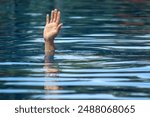 Hand of a person drowning, emerging from the water. A hand reaching out of the water. person sinking underwater. Drowning person needs help, rescue. A risk, danger for living in the sea, river, ocean.