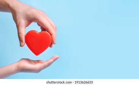 Hand person giving a heart to another person on blue background.Poster, copy space for text
