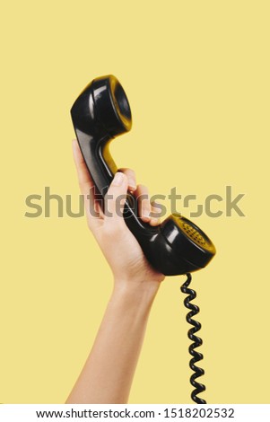 Hand of person holding black telephone receiver