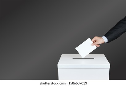 Hand Of A Person Use A Vote Into The Ballot Box In Elections. With Black Background      