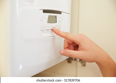 Hand Of Person Using Domestic Boiler Controls, Close Up