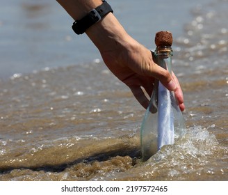 Hand Of The Person Who Collects The Bottle With A Secret Message Or A Treasure Map In The Middle Of The Sea