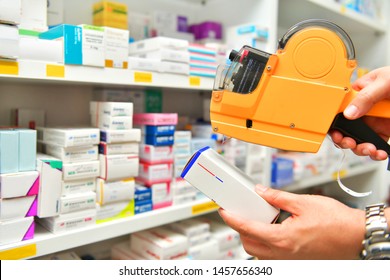 Hand Of The Pharmacist Using Yellow Labeling Gun For Sticking Price Label Of Medicine In Pharmacy Drugstore