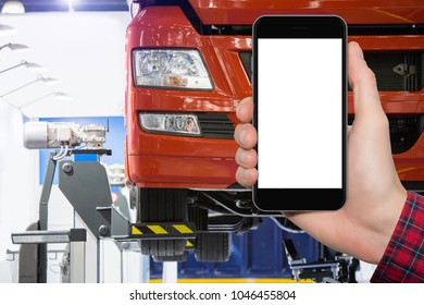 Hand With Phone On A Background Of Truck On A Lift In A Car Service